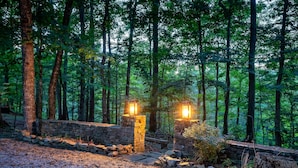 Un muro de piedra con dos faroles, rodeado de un bosque.