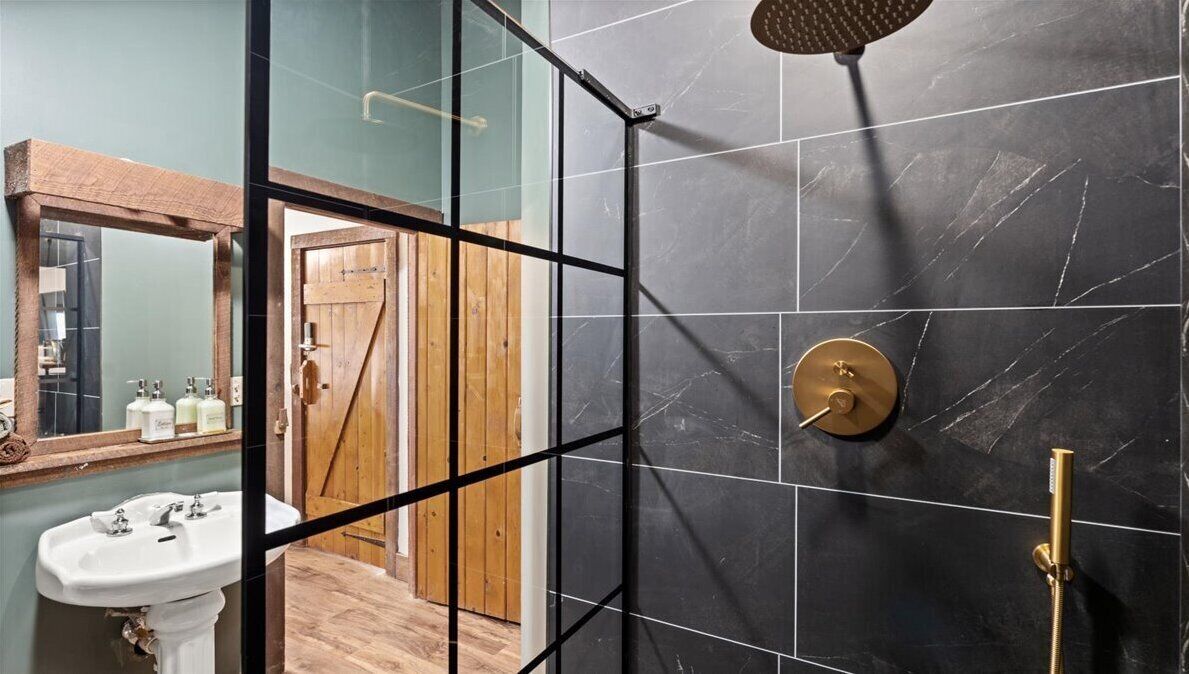 Un bagno moderno con box doccia in vetro, porta in legno e uno specchio grande.