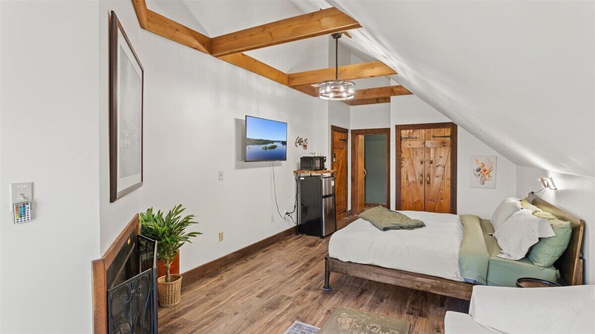 Une chambre à coucher avec un lit, une télévision, un bureau et un plafond en bois.