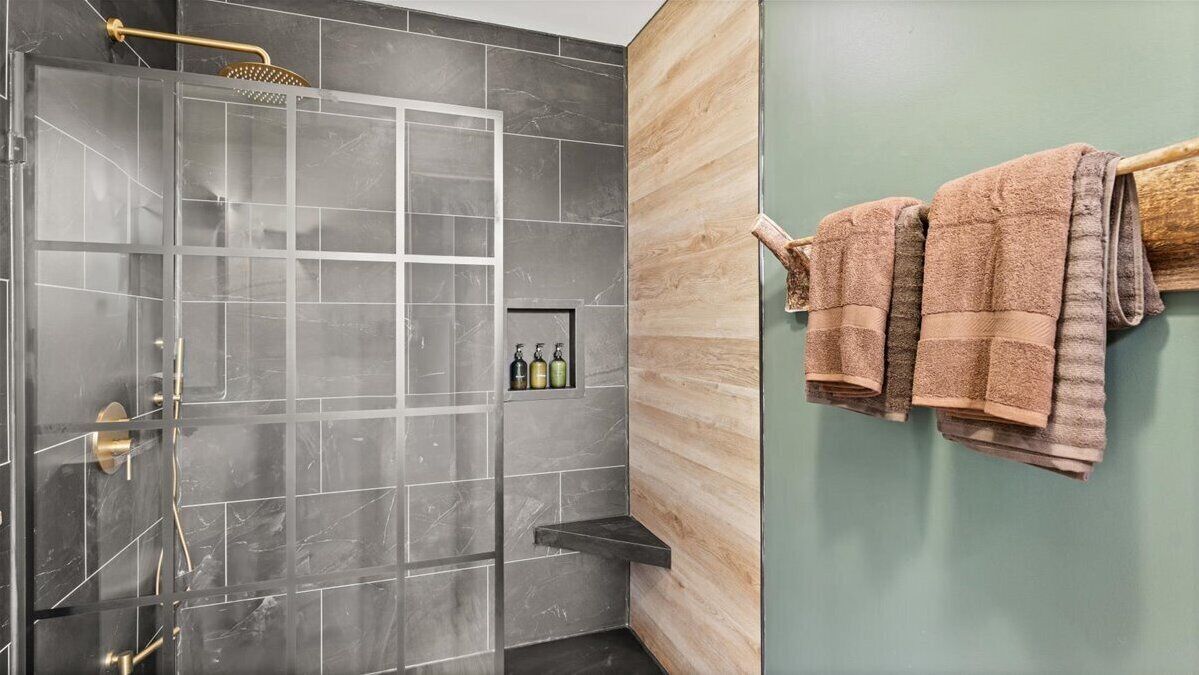 A modern bathroom with a shower, a towel rack, and a shelf with toiletries.