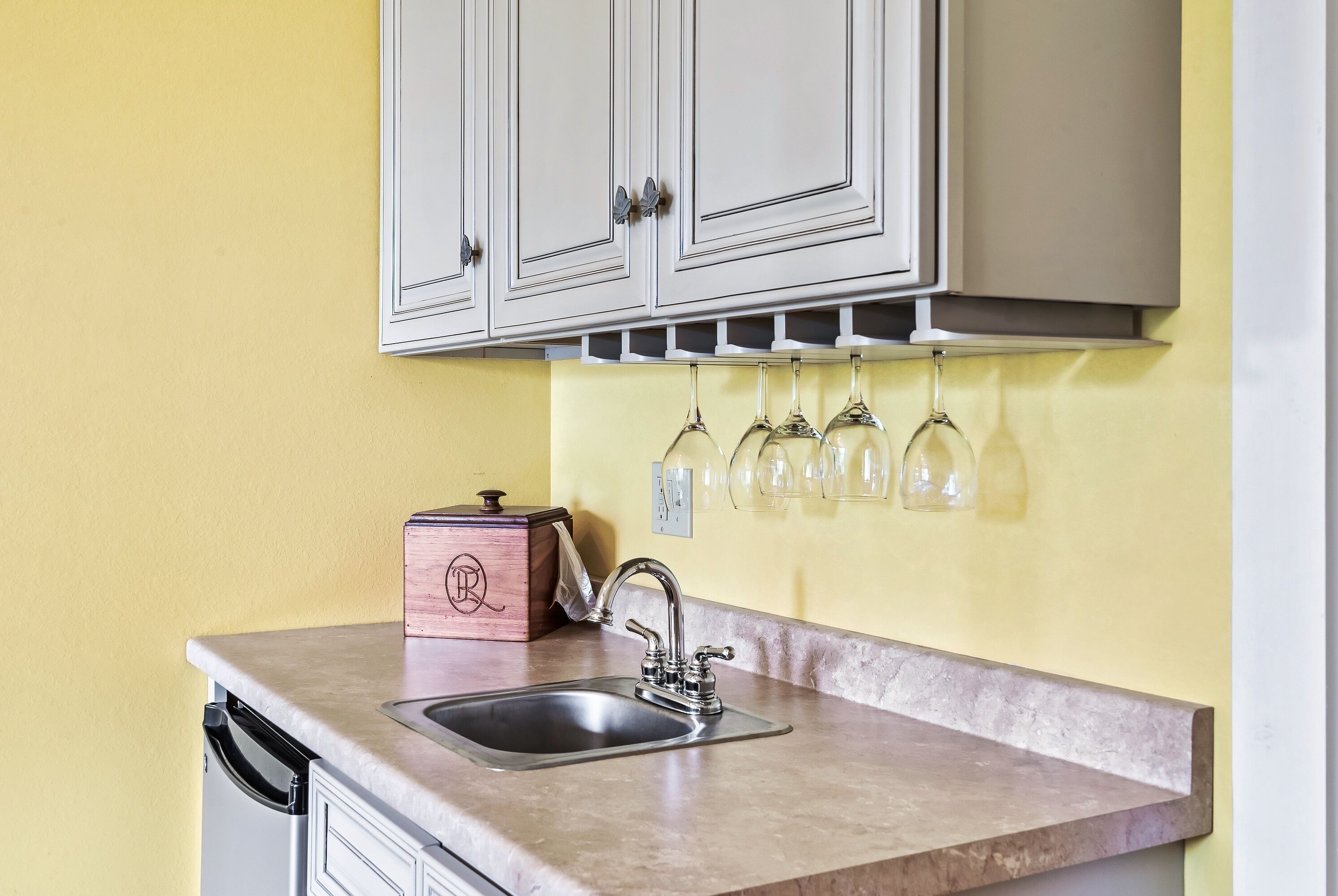 A kitchen with a sink, cabinets, and a wine rack.