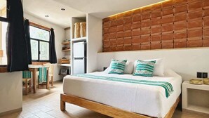 Un dormitorio moderno con cama de madera, cabecera de ladrillo y zona de comedor con mesa y sillas.