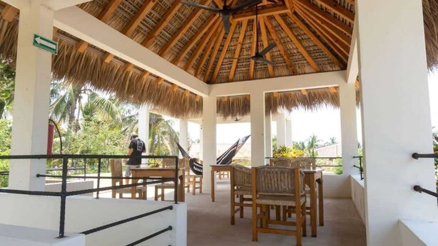 Un espacio al aire libre techado con mobiliario de madera y techo de paja.