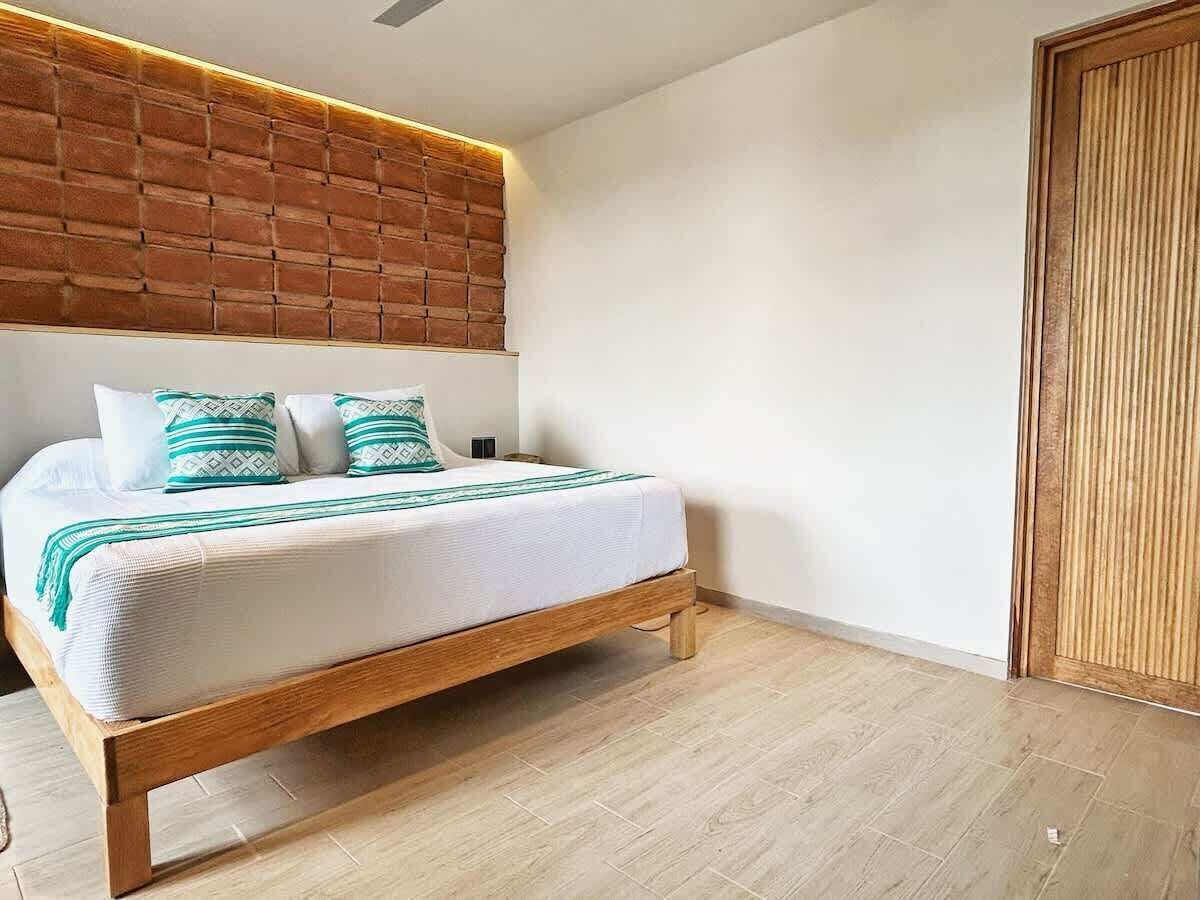 A bedroom with a wooden bed frame, white bedding, and a brick-patterned headboard.