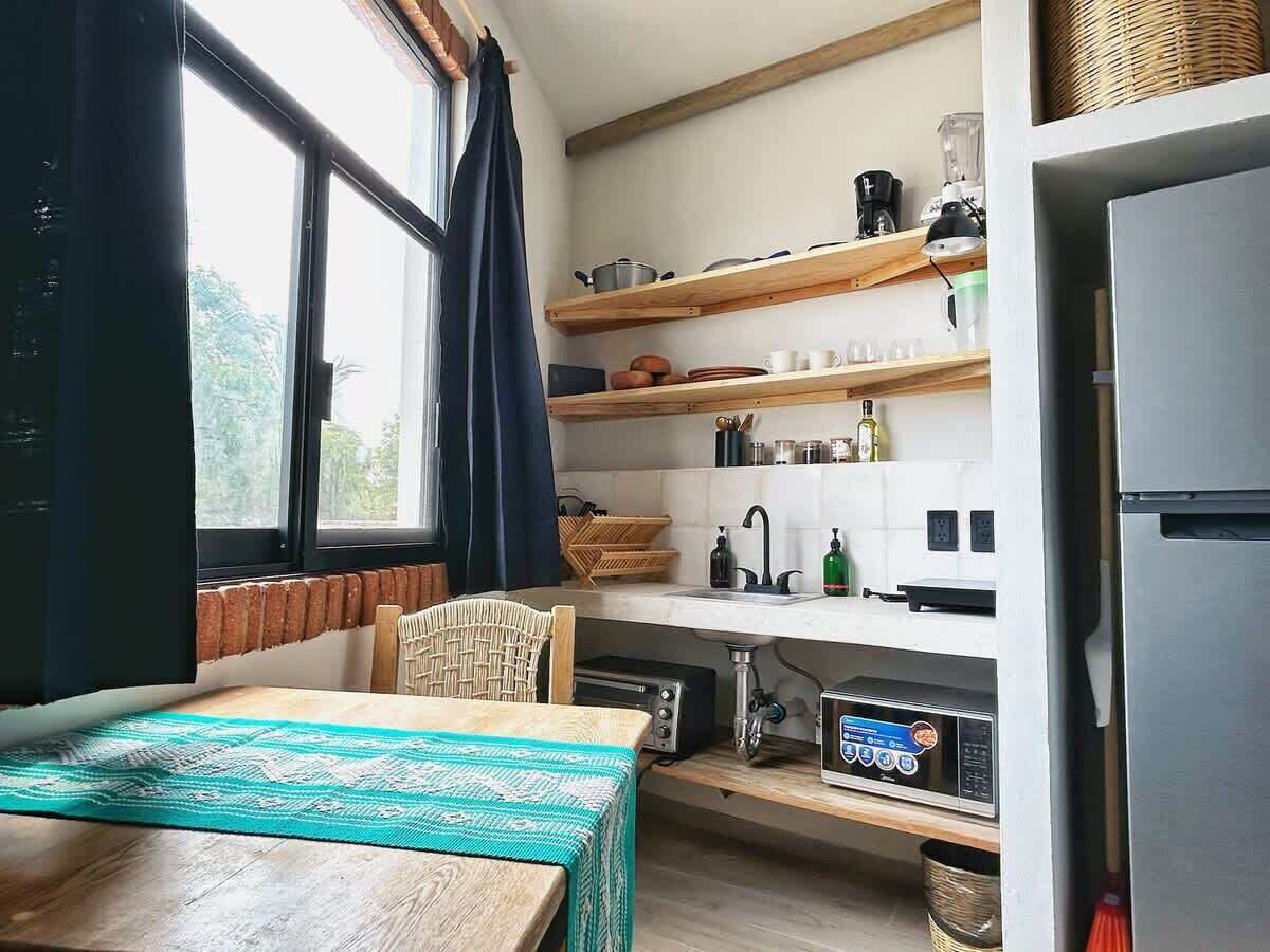 Une cuisine compacte avec un coin repas, un four à micro-ondes encastré et un réfrigérateur.