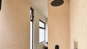 Un pasillo estrecho con paredes color beige, una ventana y una puerta con picaporte negro.