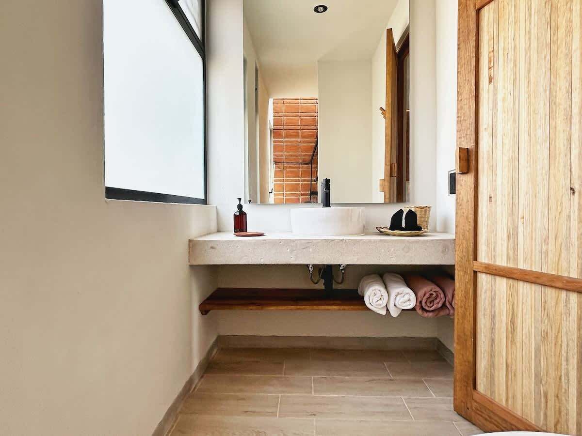 A bathroom with a white sink, wooden shelves, and a mirror.