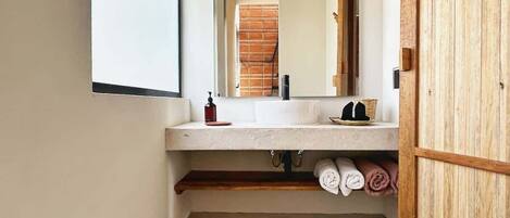 A bathroom with a white sink, wooden shelves, and a mirror.