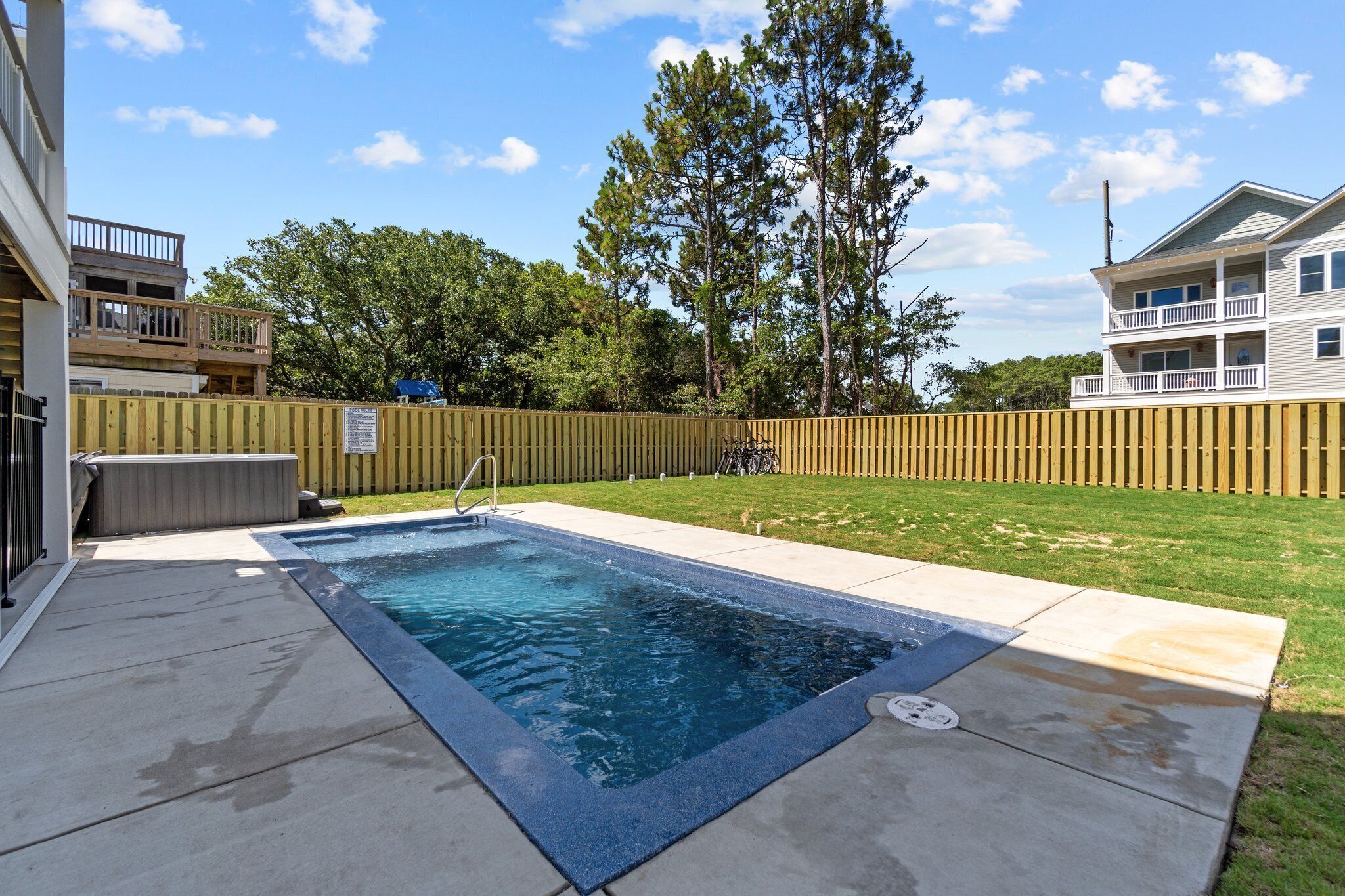 A rectangular swimming pool with a blue border, surrounded by a concrete deck.