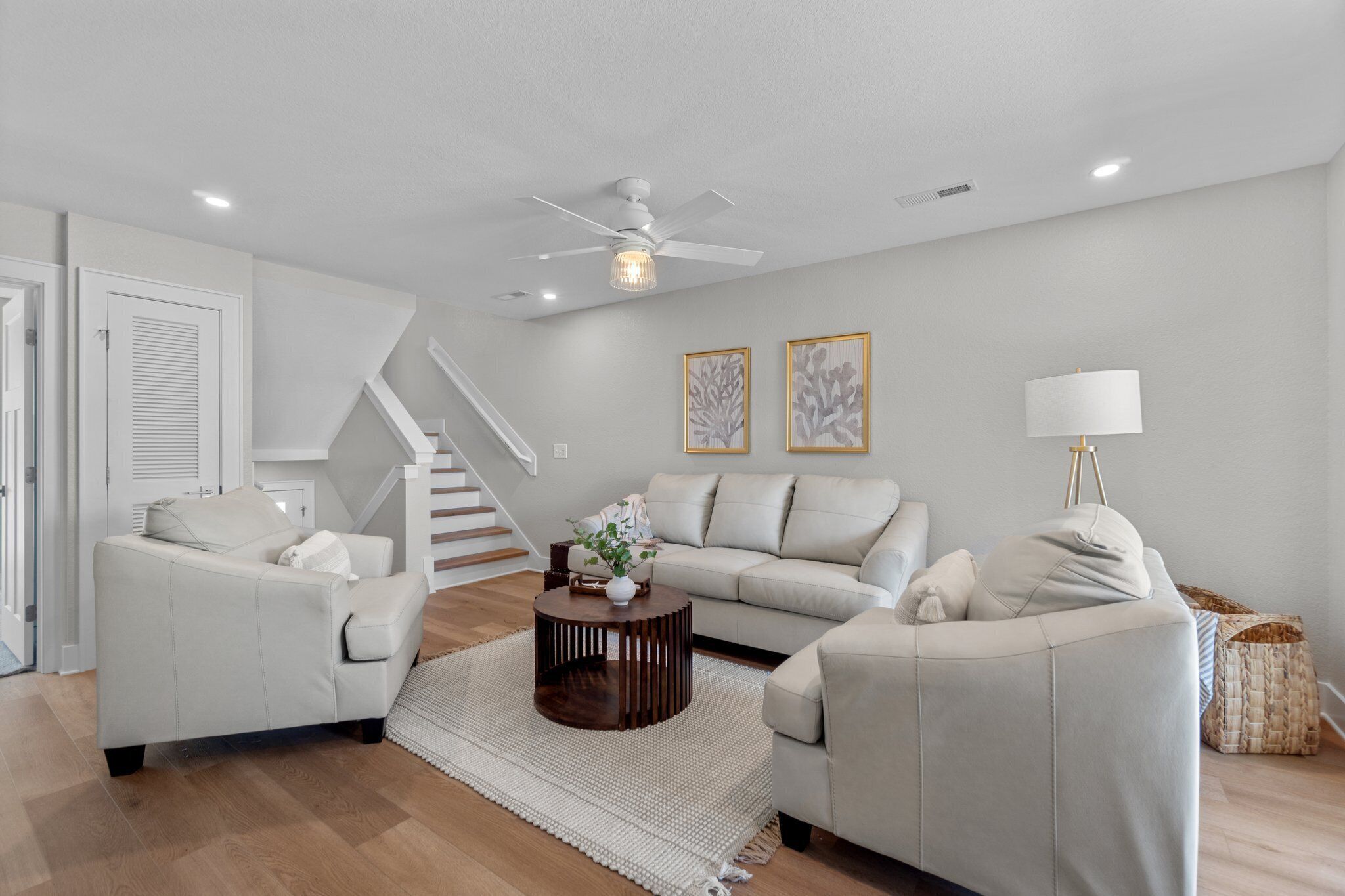 A modern living room with a sofa, two armchairs, a coffee table, and a ceiling fan.