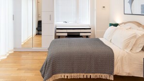 Ein modernes Schlafzimmer mit Bett, Schreibtisch und begehbarer Kleiderschrank.