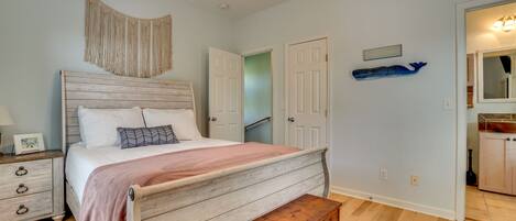 A bedroom with a wooden bed, a bench, a nightstand, and a wall-mounted macrame piece.