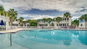 Ein Swimmingpool mit weißem Zaun und Palmen.