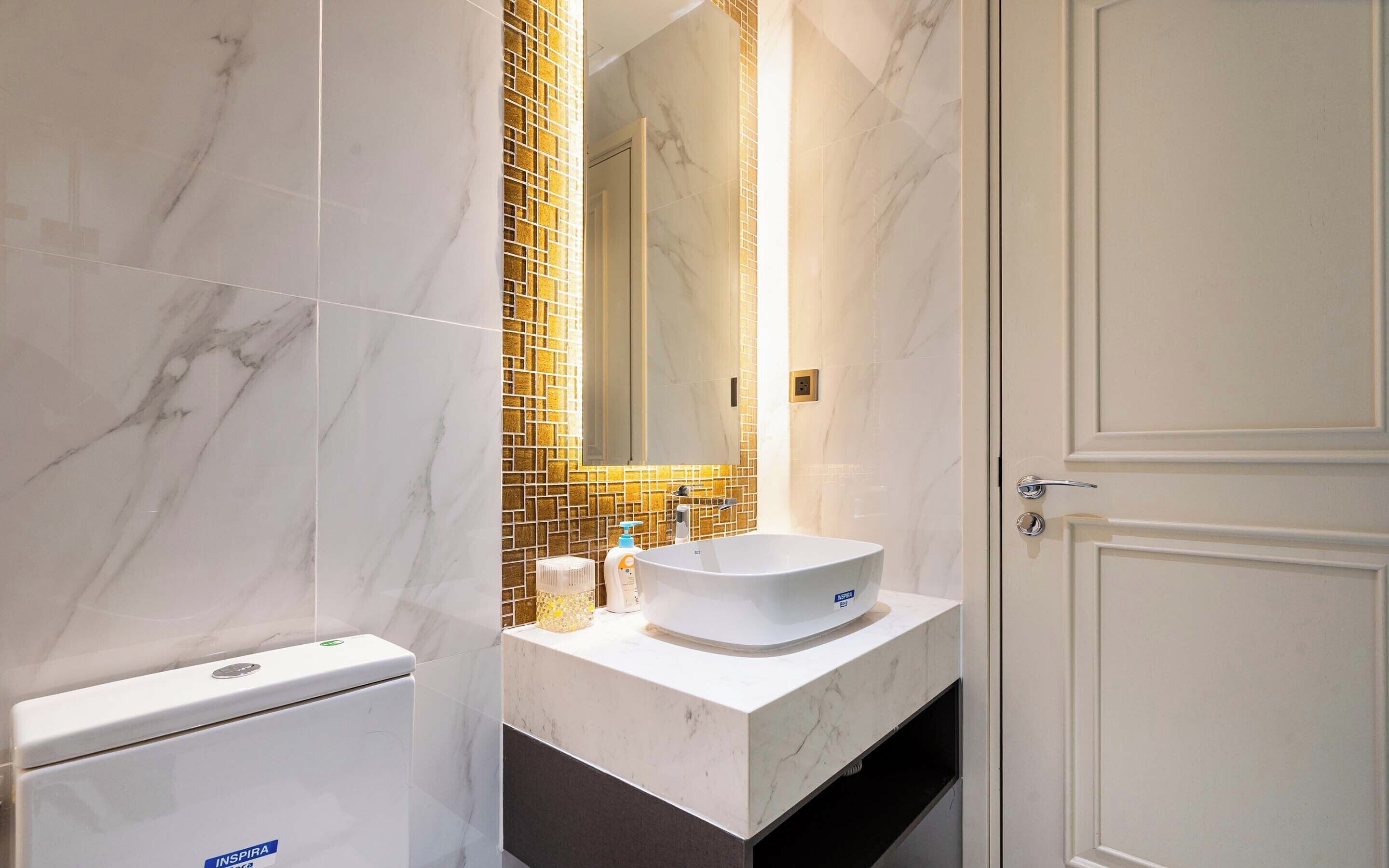 Ein Badezimmer mit einer weißen Toilette, einem Waschbecken mit weißer Schüssel und einem Spiegel über dem Waschbecken.