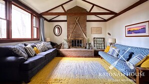 A spacious living room with a fireplace, two sofas, and a large window.