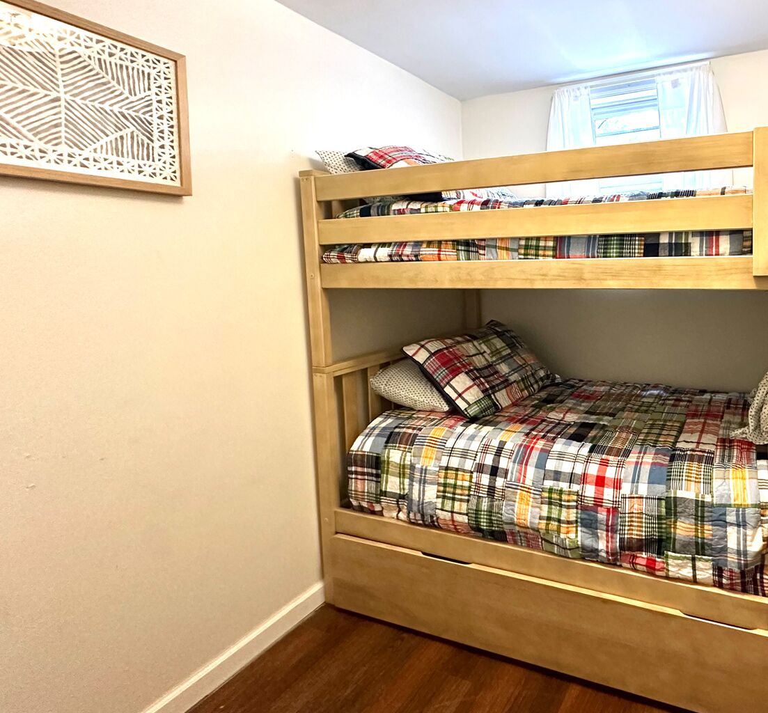 A bunk bed with a plaid bedspread and pillows.