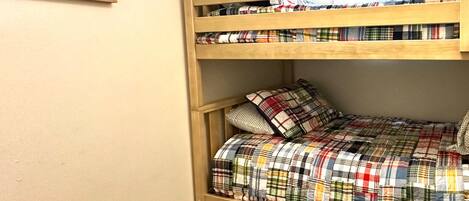 A bunk bed with a plaid bedspread and pillows.
