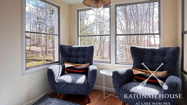 Two armchairs with patterned cushions in a room with large windows, a small round table, and a wooden floor.