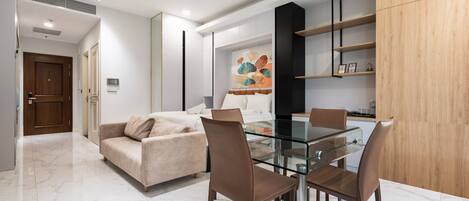 Ein modernes Wohnzimmer mit einem Glastisch, Ledersesseln, einem beigefarbenen Sofa und einem Holzschrank.