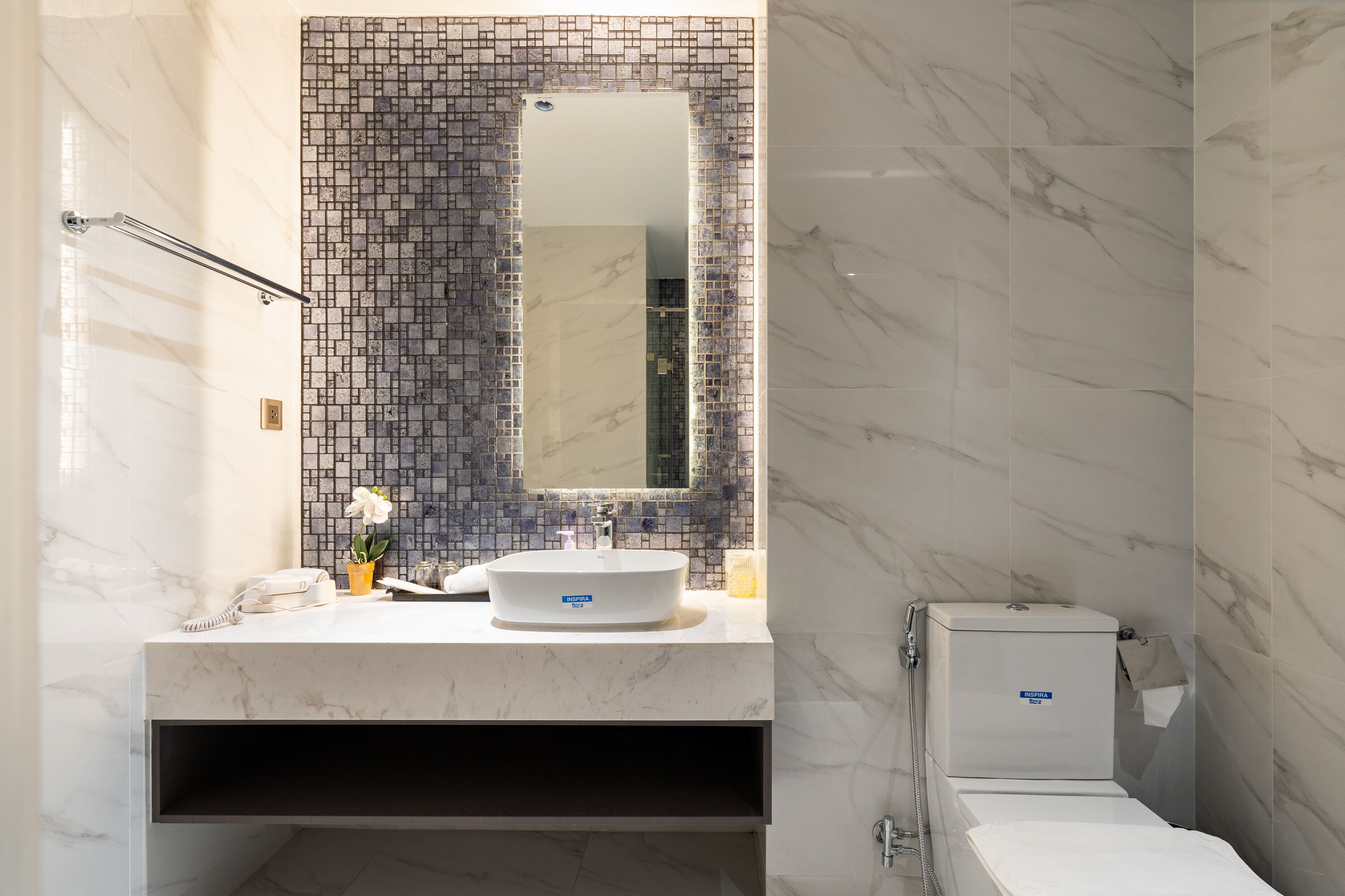Une salle de bain moderne avec un meuble-lavabo en marbre, un grand miroir et des toilettes.