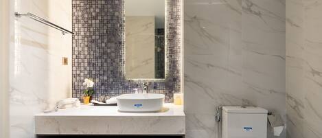 Une salle de bain moderne avec un meuble-lavabo en marbre, un grand miroir et des toilettes.