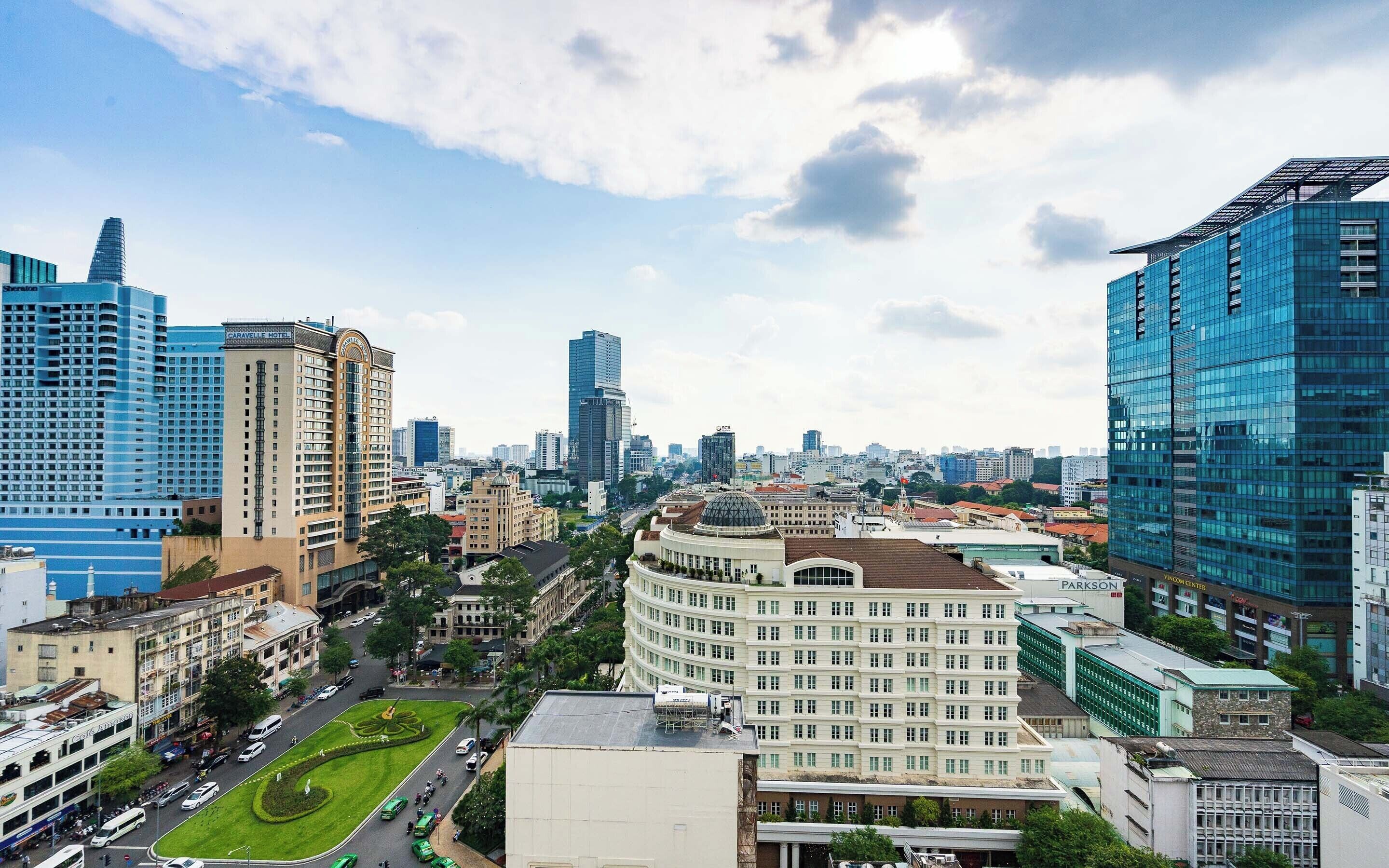 A cityscape with modern high-rise buildings, a central round building with a dome, and a green park area.