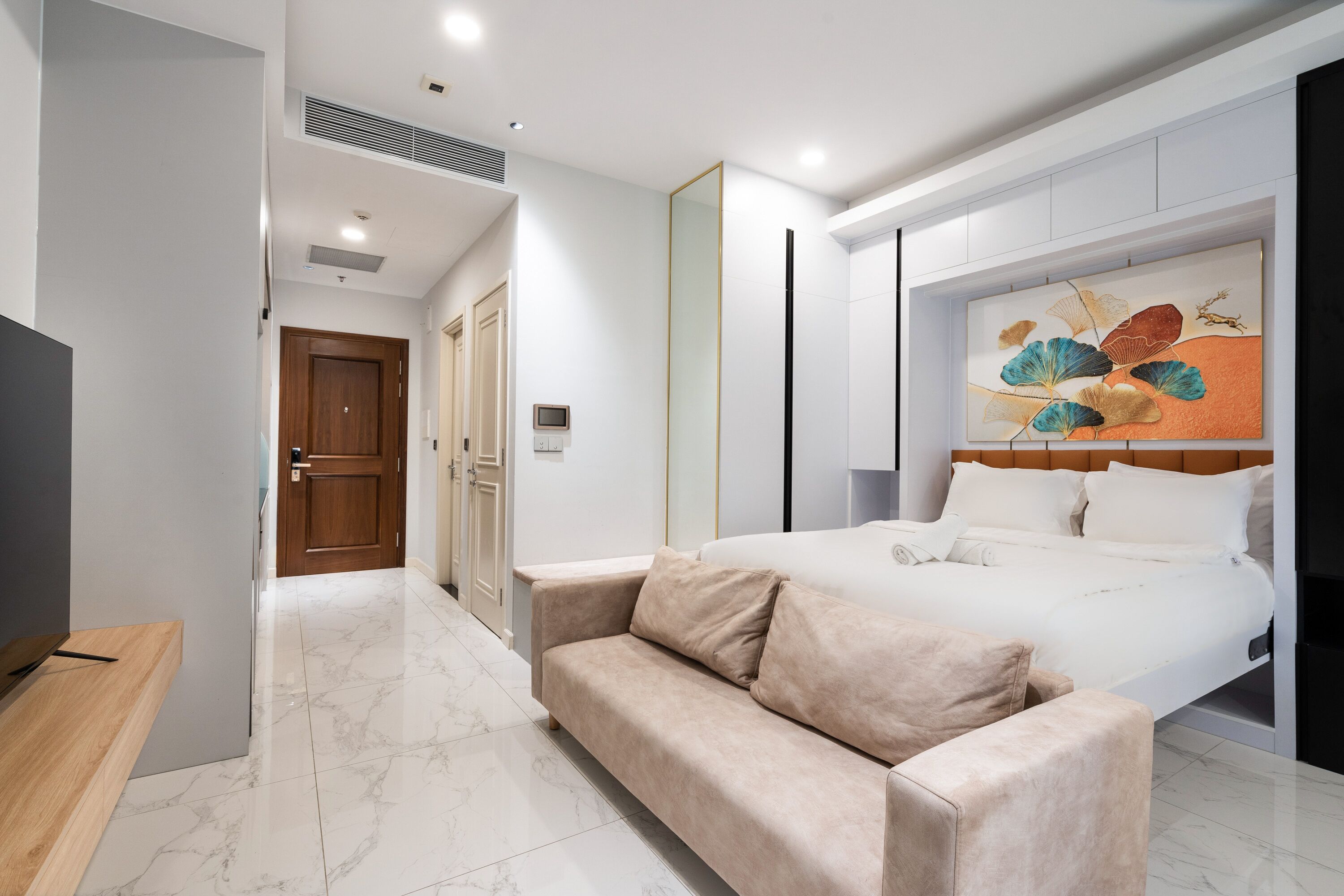 Une chambre d’hôtel moderne avec un grand lit, un canapé, une télévision et un tableau au mur.
