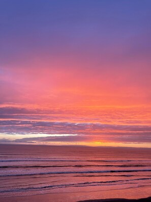 Ein Sonnenuntergang über ruhigem Meer unter wolkenlosem Himmel.
