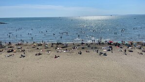 Ein Strand mit badenden und sonnenden Personen.