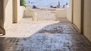 Blick von einem Balkon auf einen Strand mit badenden und sonnenden Personen.