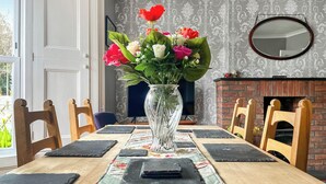 A dining table with a floral centerpiece, black placemats, and wooden chairs. - Escape to our pet-friendly haven nestled in the heart of Carmarthen. (Carmarthen)