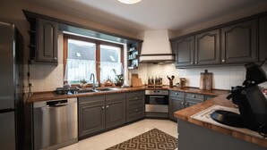 Een moderne keuken met donkere kastjes, roestvrijstalen apparatuur en een houten aanrecht.