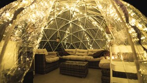Een iglo-achtig gebouw met een geometrisch lichtpatroon, een bank en een kleine tafel binnen.