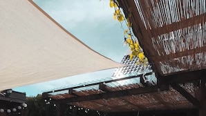 Un área de hidromasaje al aire libre con una pérgola de madera, una zona de estar cubierta y un patio con baldosas.
