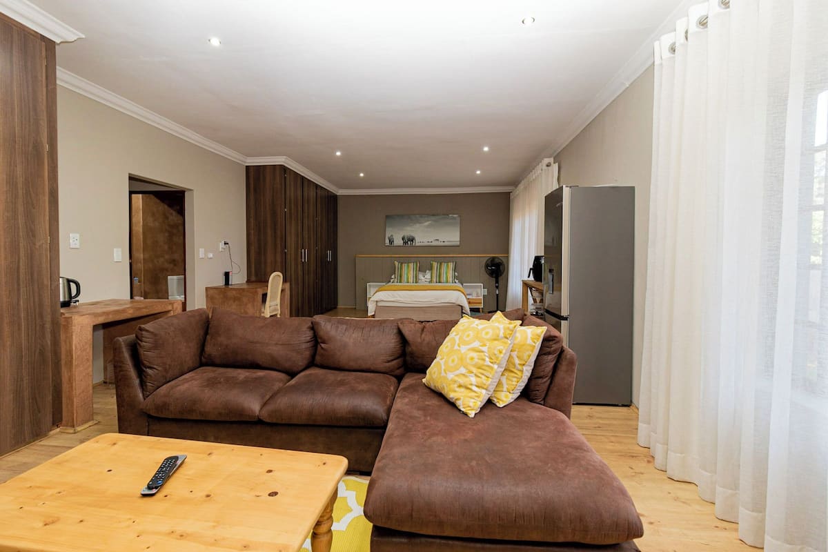 Een woonkamer met een bruine modulaire bank, een houten salontafel en een afstandsbediening erop.