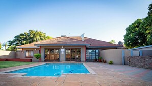 Une maison avec une piscine, un patio couvert et un mur en briques.