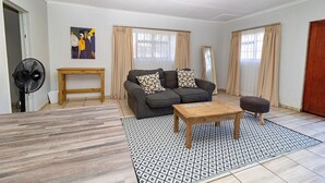 Un salon comprenant un canapé, une table basse, un ventilateur et une table d’appoint en bois.