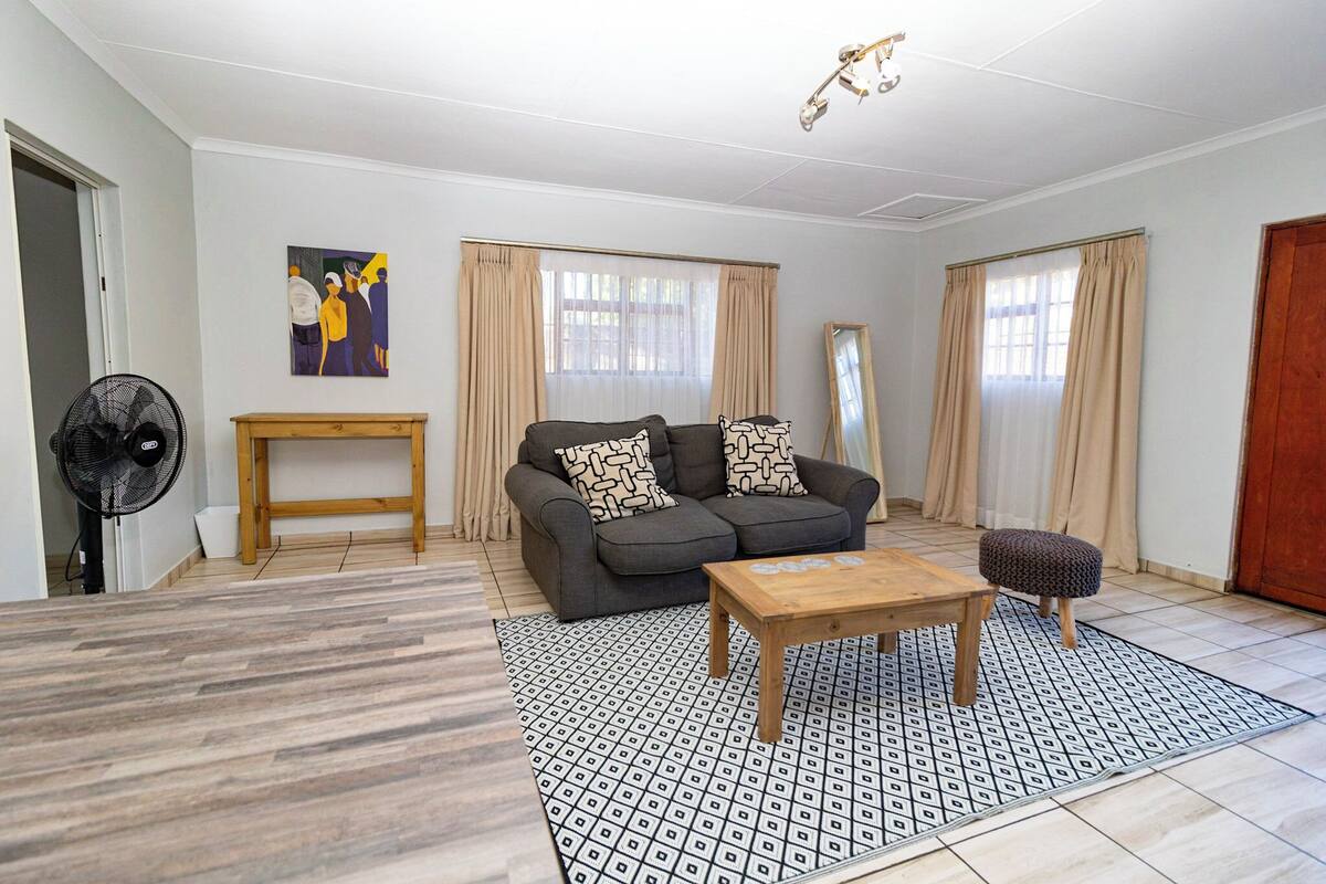 Een woonkamer met een bank, een salontafel, een ventilator en een houten bijzettafeltje.