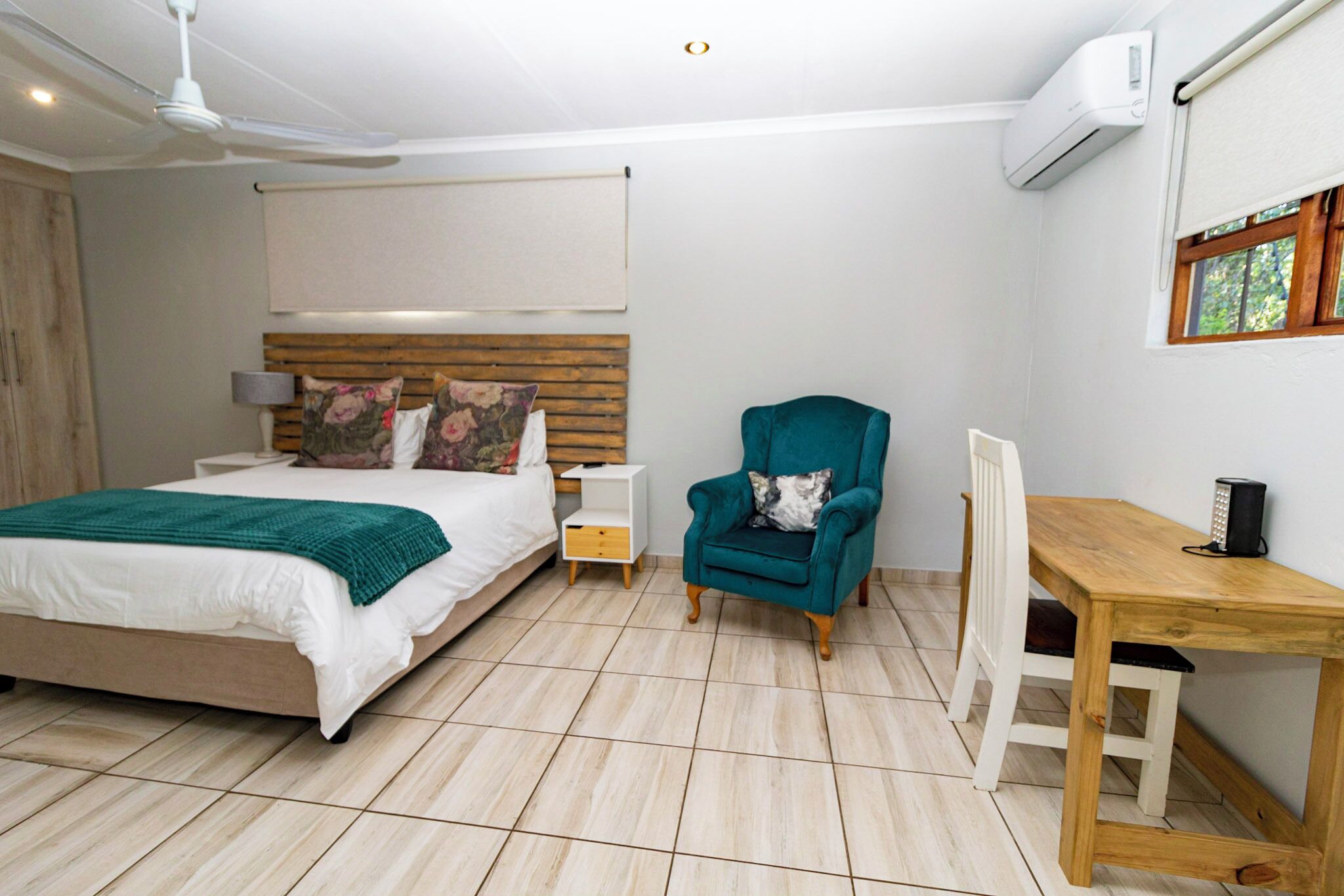 Un dormitorio con cama, escritorio, silla y ventilador de techo.