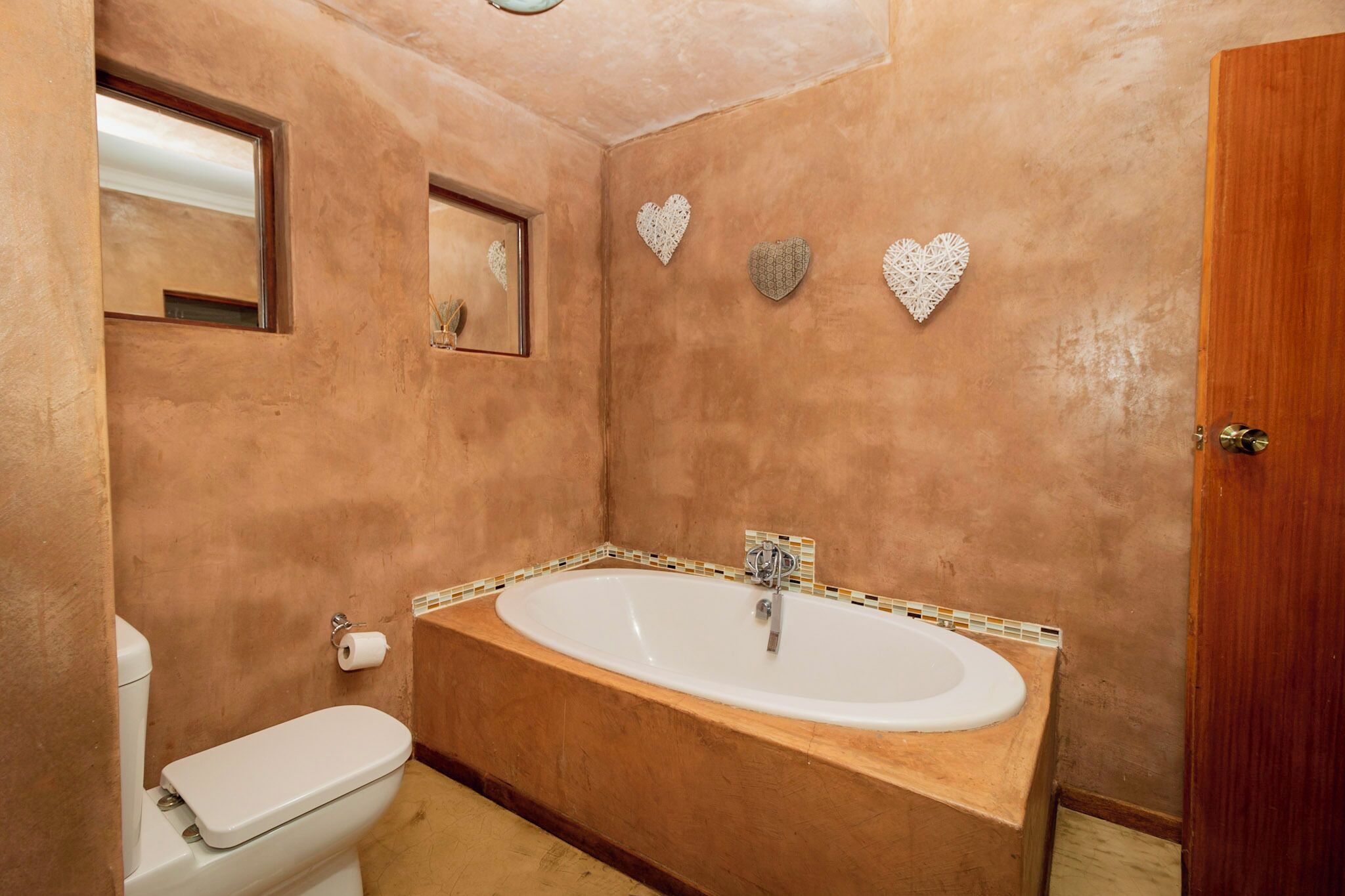 A bathroom with a bathtub, toilet, and a wooden door.
