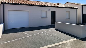 Um edifício com telhado ladrilhado, porta de garagem e uma pequena janela.