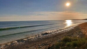 Uma praia com costa rochosa e ondas suaves batendo na areia.