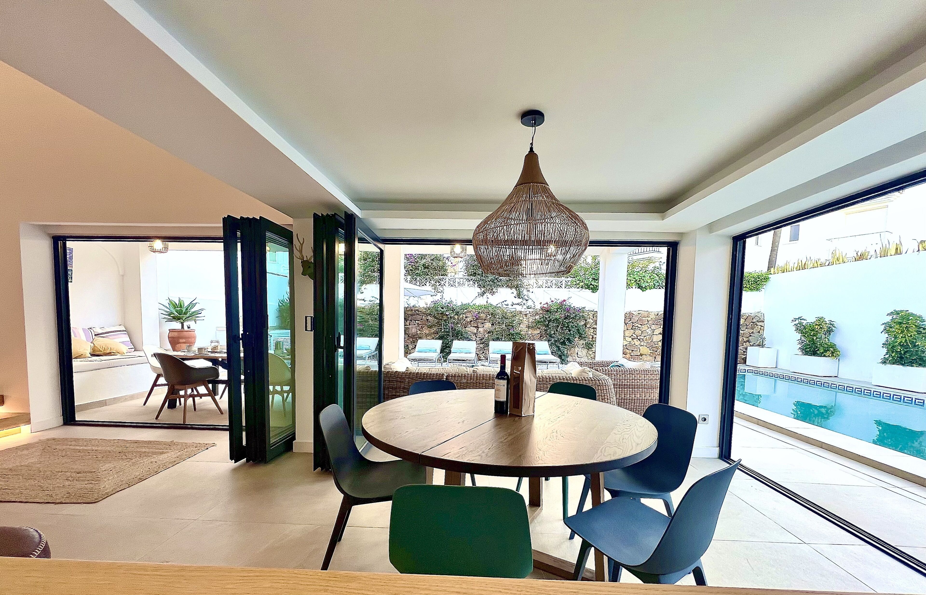 A modern dining area with a round table, chairs, and a hanging light fixture.