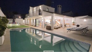 Ett modernt hus med en swimmingpool, en balkong och en väl upplyst interiör.