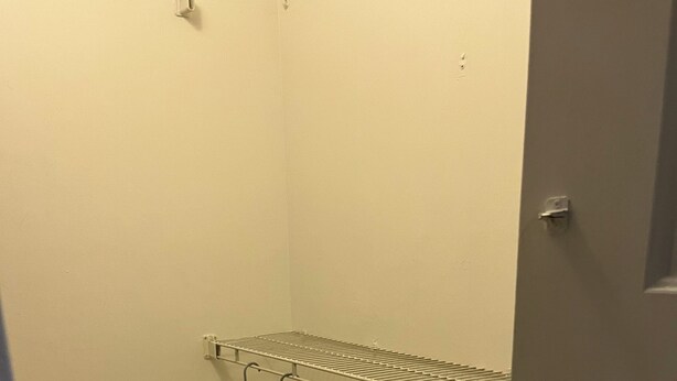 A small, narrow room with a tiled floor and a metal drying rack mounted on the wall.