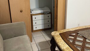 Een kamer met een bed, een houten kast en een betegelde vloer.