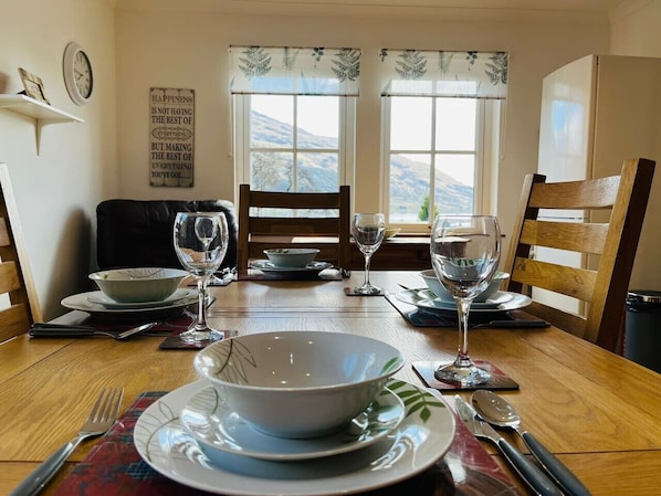 Enjoy meals with a view of the surrounding mountains from this dining area, featuring a table for four and comfortable seating.