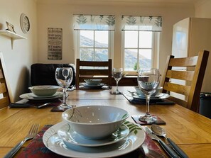 A dining table set for four with a view of mountains through the windows. - Avoca House in the village of Onich (Fort William)