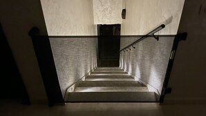 A staircase with a metal railing and a textured wall.