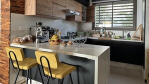 A modern kitchen with a marble countertop, wooden cabinets, and a built-in island with bar stools.
